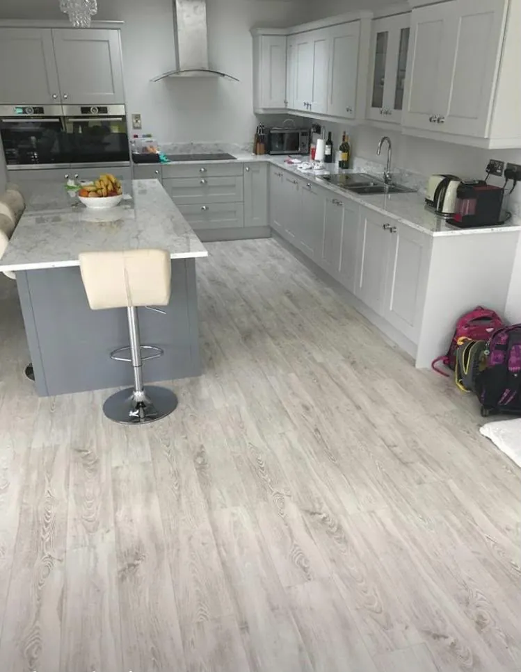 Renovated open-plan kitchen with grey shaker units and new plank flooring